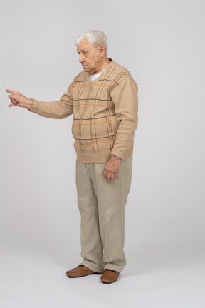 Seitenansicht eines alten mannes in freizeitkleidung, der mit dem finger zeigt
