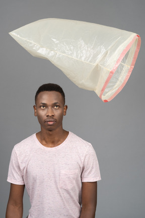 Close-up joven africano macho viendo una bolsa de plástico volando sobre él