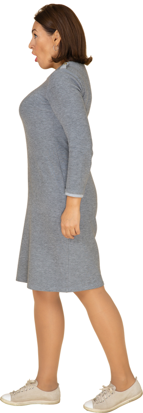 Vista lateral de uma mulher impressionada em um vestido cinza