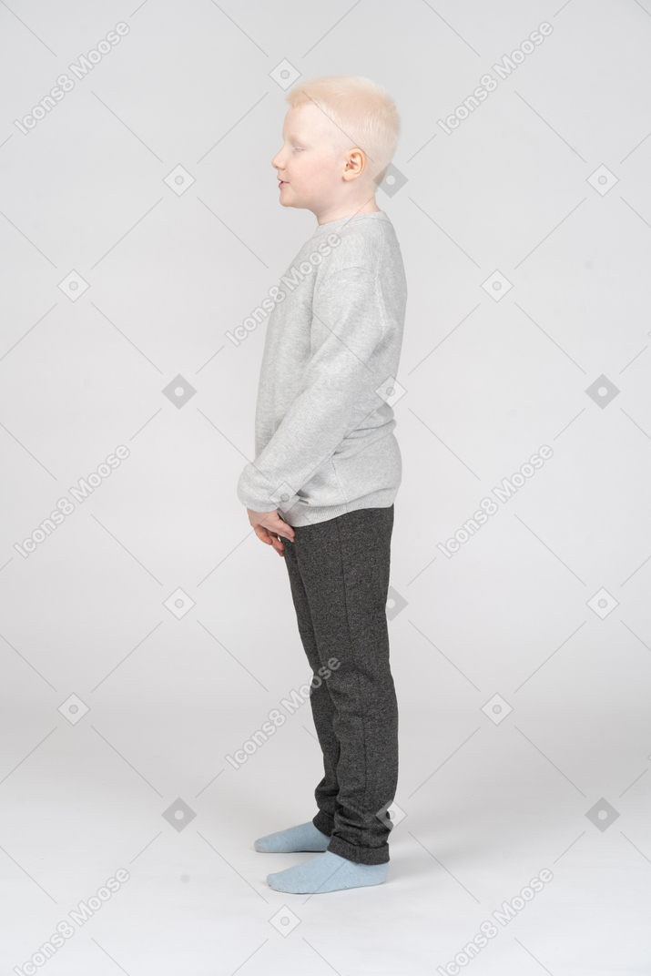 Вид сбоку на спокойного маленького мальчика со сложенными руками