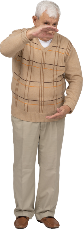 Vista frontal de um velho em roupas casuais, mostrando o tamanho de algo