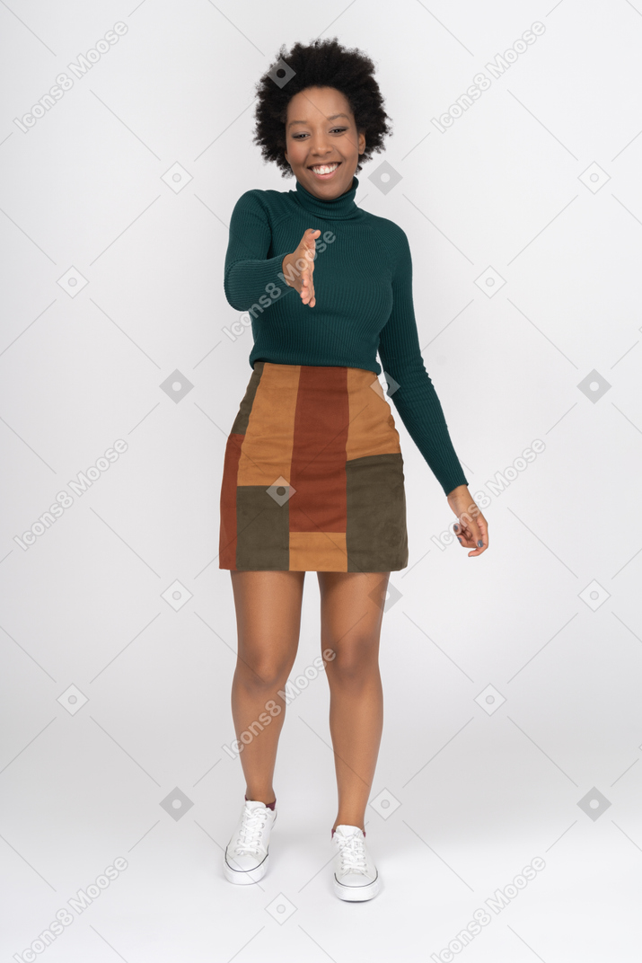 Menina africana sorridente em pé com a mão estendida pronta para aperto de mão