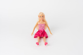 Eine schöne barbie-puppe in einem glänzenden rosa kleid und in einem rosa sitzen der hohen absätze lokalisiert gegen einen normalen weißen hintergrund