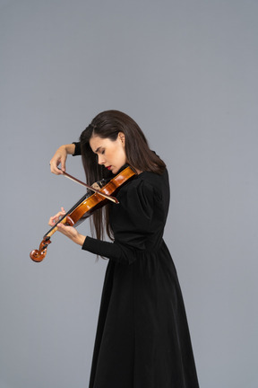 Close-up de uma jovem de vestido preto tocando violino