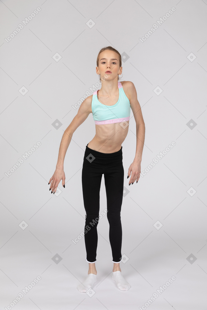 Vista frontal de una jovencita en ropa deportiva inclinando los hombros