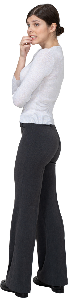 Vista posteriore di tre quarti di una giovane donna nervosa in abiti da ufficio che tocca il mento