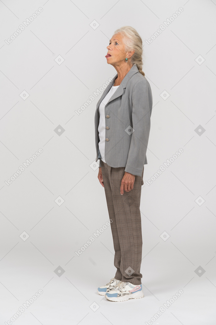 Vue latérale d'une vieille dame en costume montrant la langue