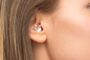 A close up of a woman's ear with a woman and a mannequin inside