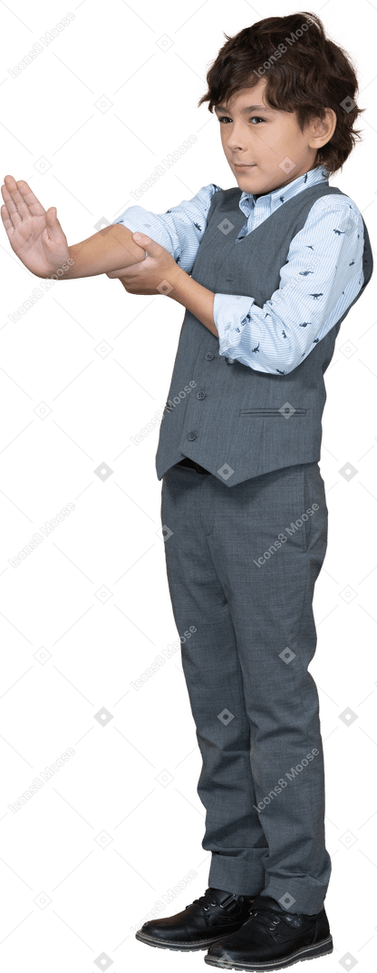 Vue latérale d'un garçon en costume gris montrant un panneau d'arrêt