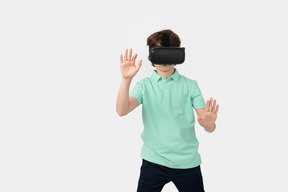 Garçon dans un casque de réalité virtuelle touchant un mur invisible