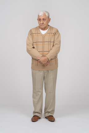 一位穿着休闲服的老人双手交叉站立的正面图