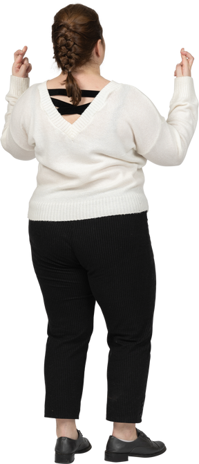 Rear view of a plus size woman in casual clothes crossing fingers