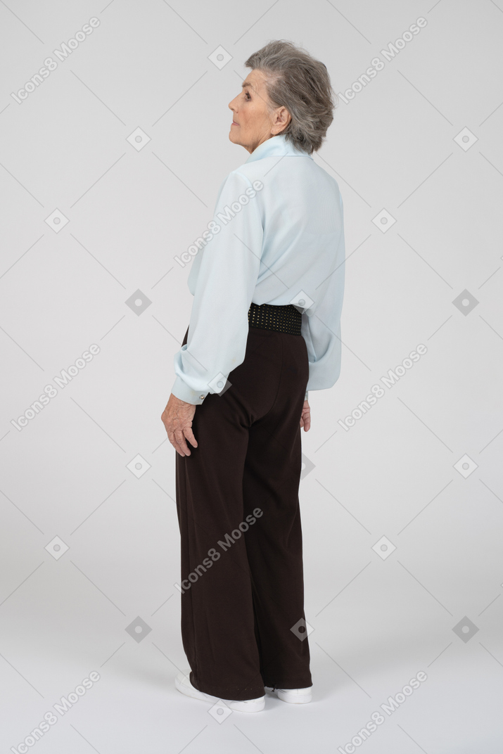 Three-quarter back view of an old woman looking aside and leaning back slightly
