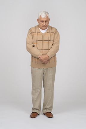 Front view of an old man in casual clothes looking down