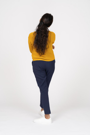 Rear view of a girl in casual clothes posing with crossed arms