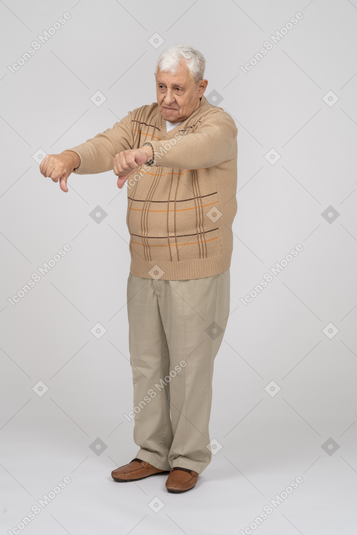 Vorderansicht eines alten mannes in freizeitkleidung mit daumen nach unten