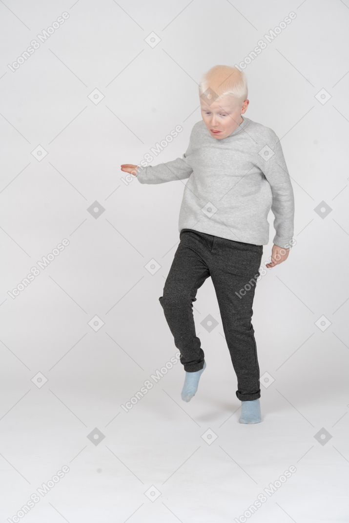 Vista di tre quarti di un ragazzo che salta su una gamba sola