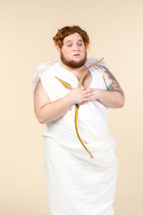 Sad looking big guy dressed as a cupid holding bow