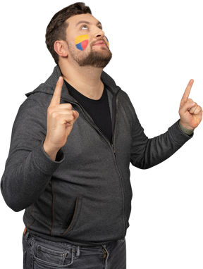 Three-quarter view of a male football fan with colorful face art raising fingers