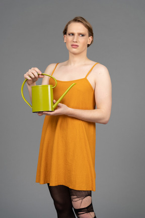 Young genderfluid person holding a watering can while looking confused
