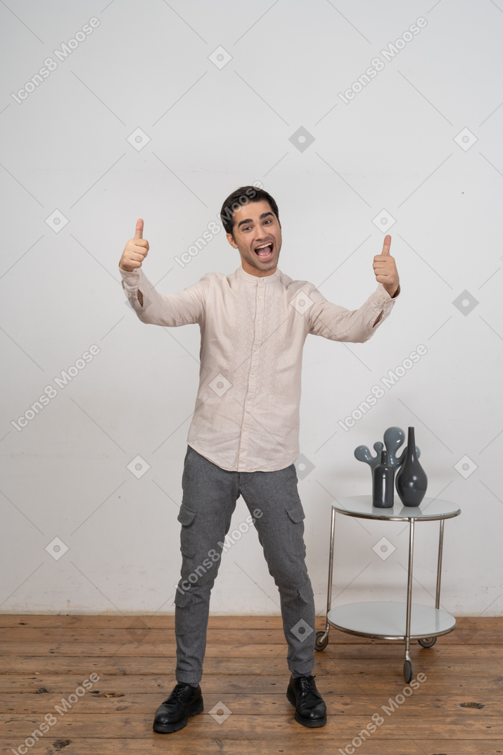 Front view of a happy man in casual clothes showing thumbs up