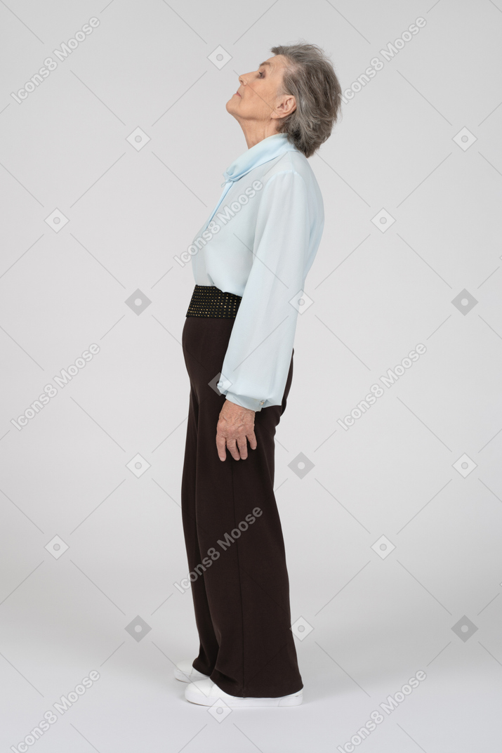 Вид сбоку на пожилую женщину, стоящую с поднятой головой