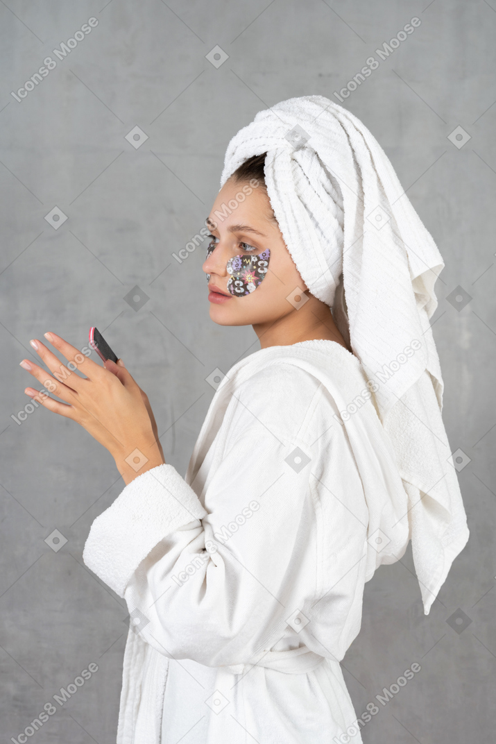 Vista lateral de uma mulher lixando as unhas