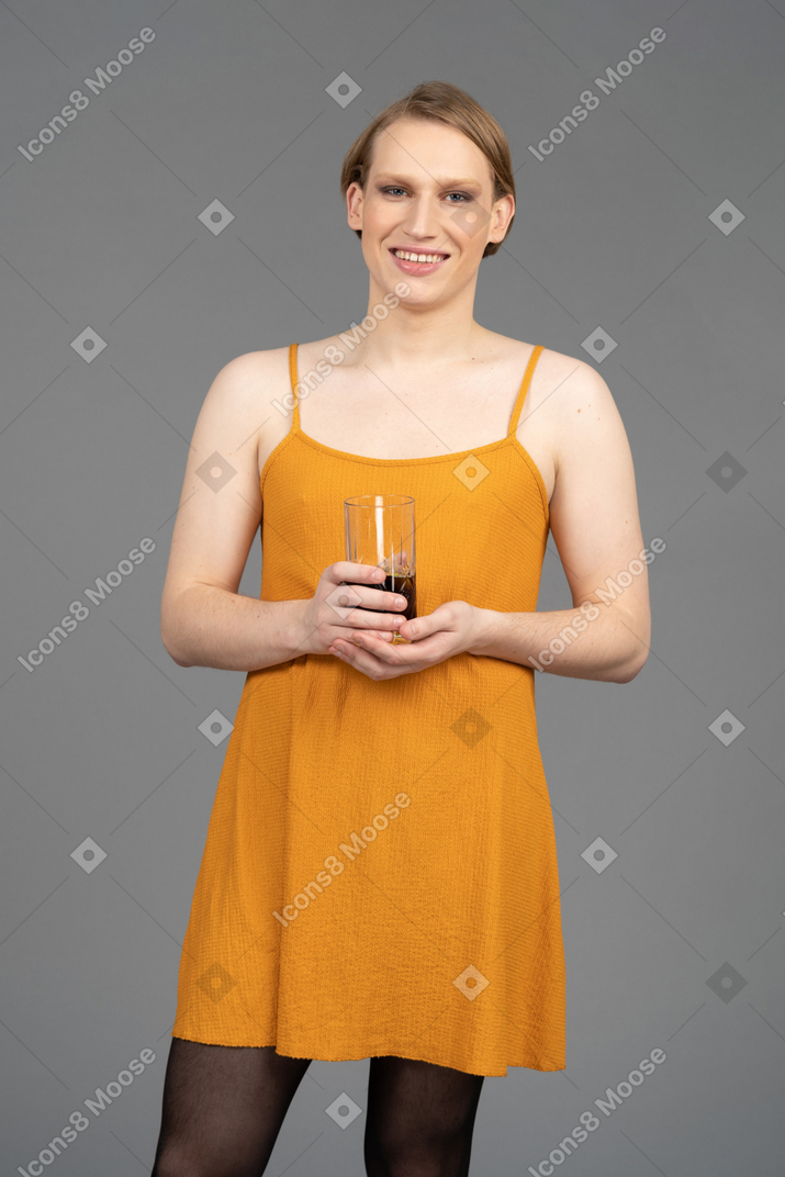 Young genderqueer person holding a drink & smiling cheerfully