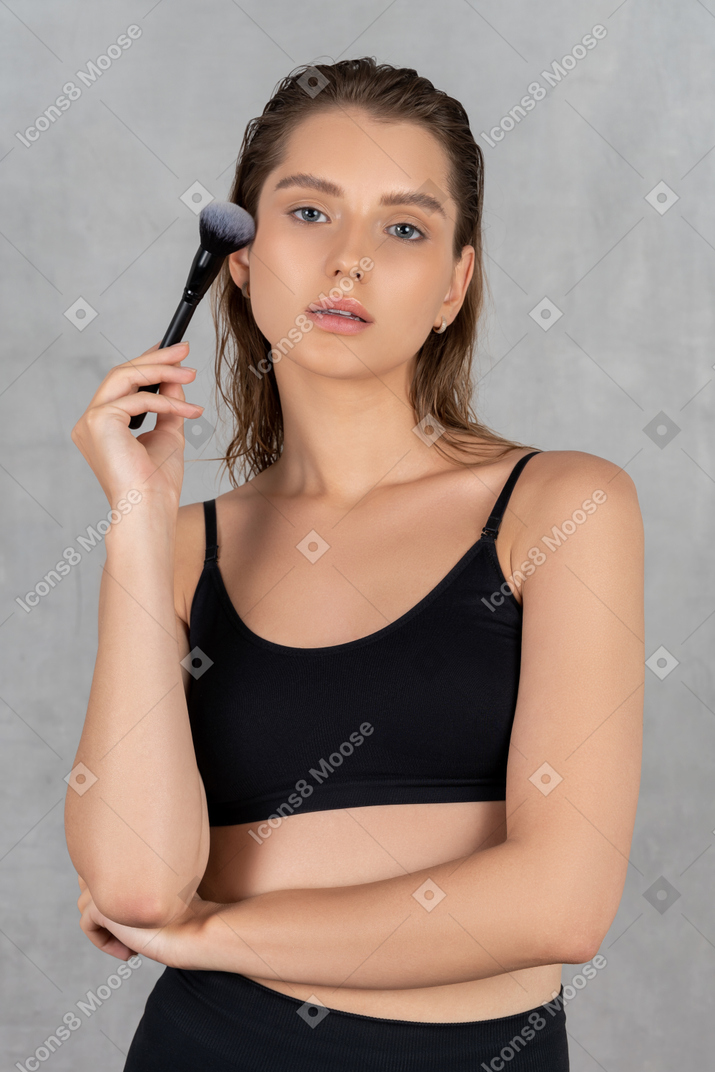 Молодая женщина держит кисточку для макияжа