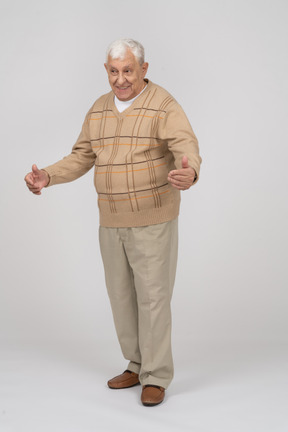 Front view of a happy old man in casual clothes standing with outstretched arms