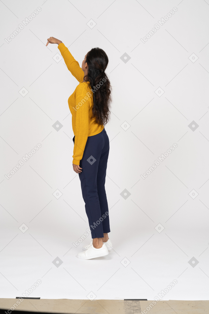 腕を上げて立っているカジュアルな服装の女の子の側面図