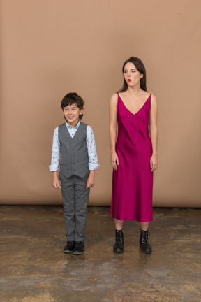 Mujer en vestido rojo de pie con niño sonriente