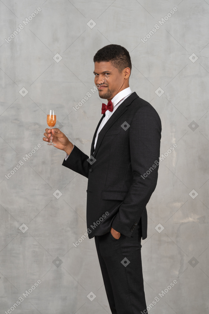Jovem de aparência enojada em pé com uma taça de champanhe