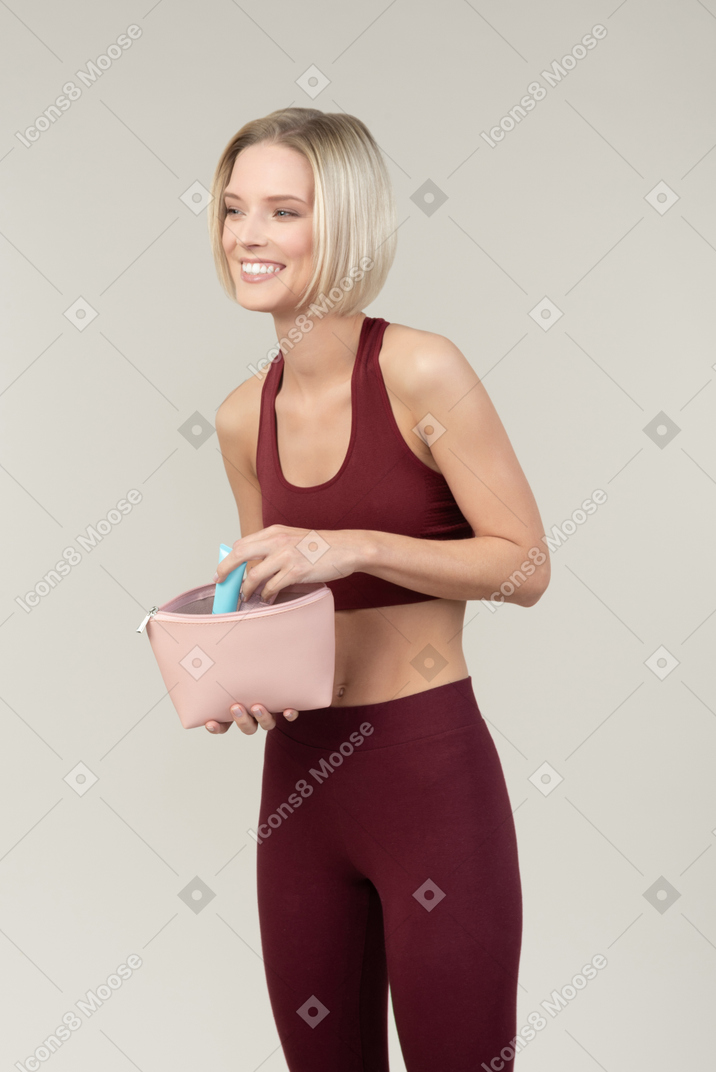 Smiling young woman holding cosmetic bag