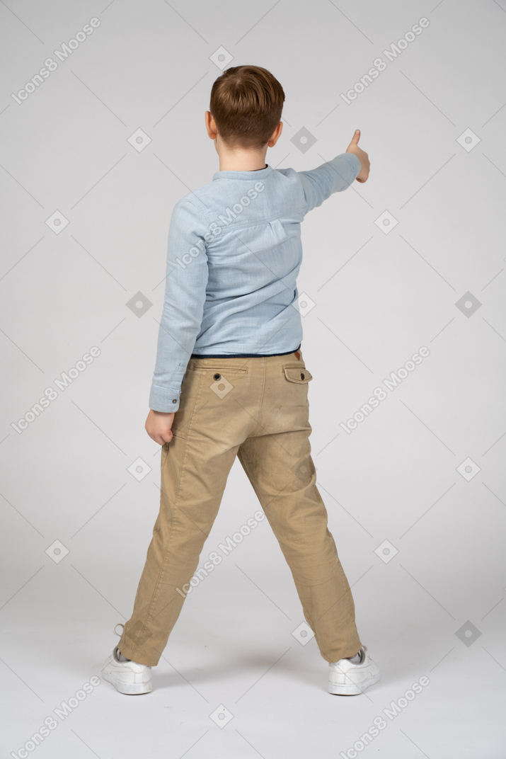 Vista traseira de um menino mostrando o polegar