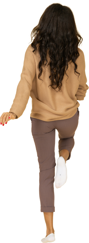Vista posteriore di una giovane femmina dalla pelle scura in marcia alzando la gamba