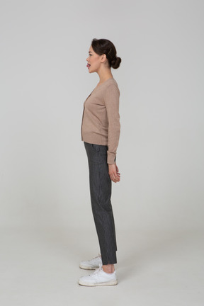 Side view of a young lady in pullover and pants showing tongue