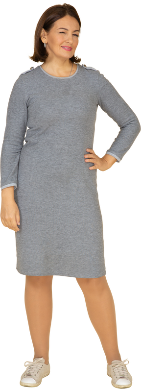 Vista frontale di una donna in abito grigio in piedi con la mano sull'anca