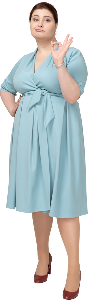 一个穿着蓝色裙子的女人的正面图，上面有 ok 的手势