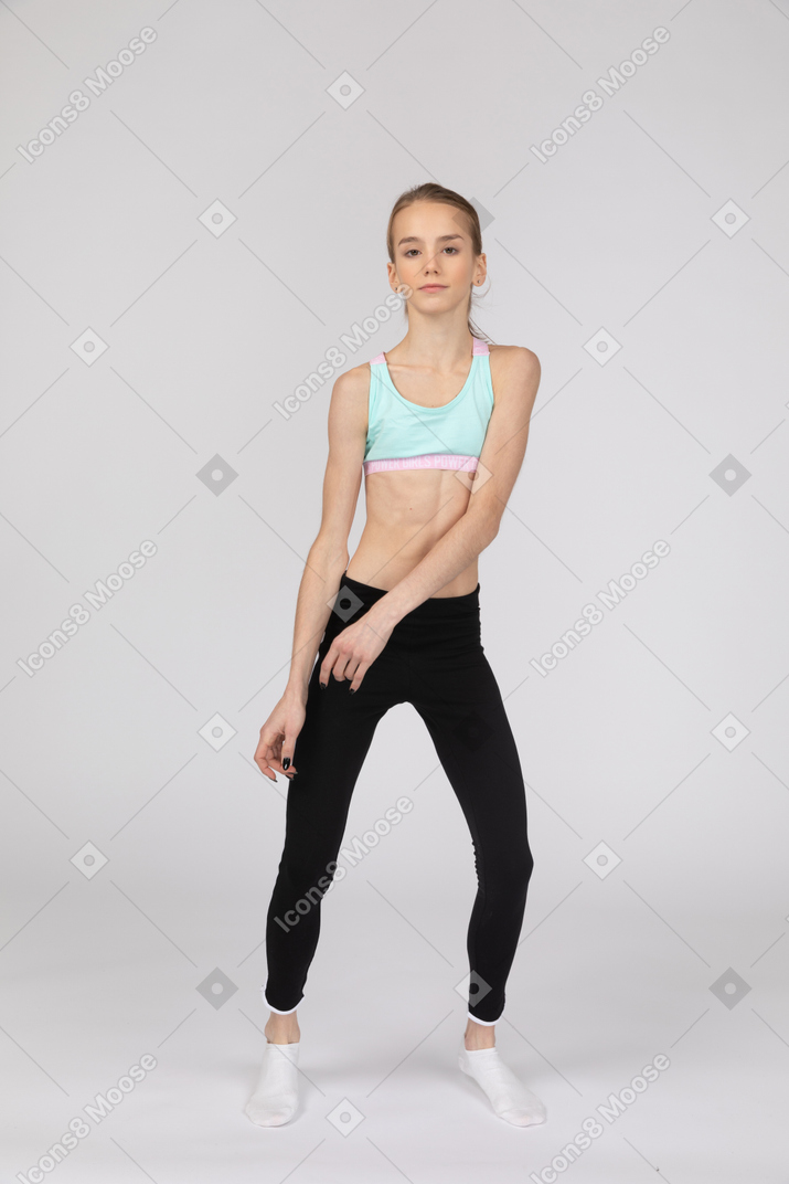 一个年轻的女孩，在弯曲膝盖的运动服的前视图