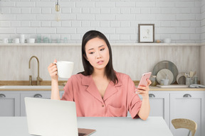 A woman sitting at a table with a cup of coffee and a laptop