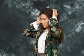 Thoughtful businesswoman in green silk jacket touching her hair