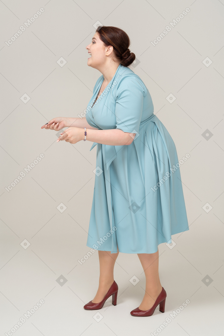 一个穿着蓝色裙子摆姿势的女人的侧视图