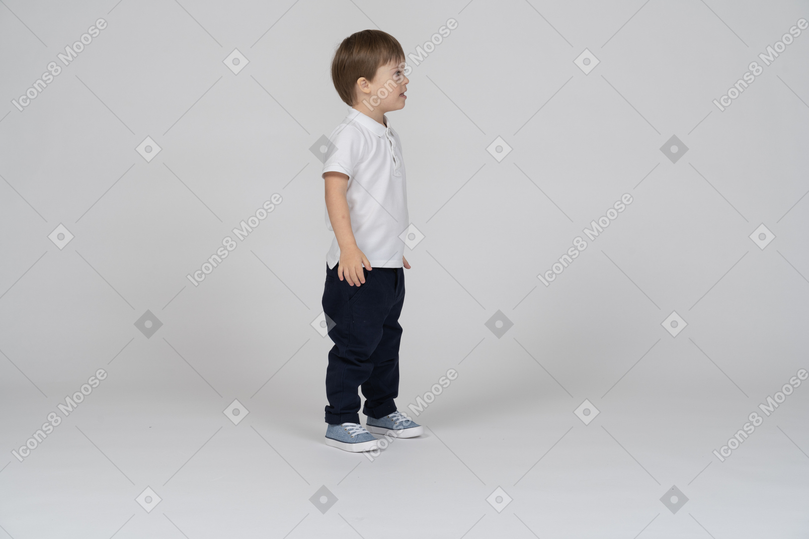 Side view of a little boy standing with arms at side
