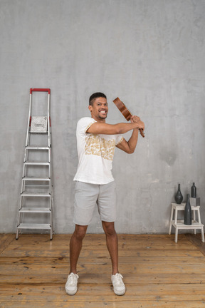 Front view of a man swinging an ukulele angrily like a bat