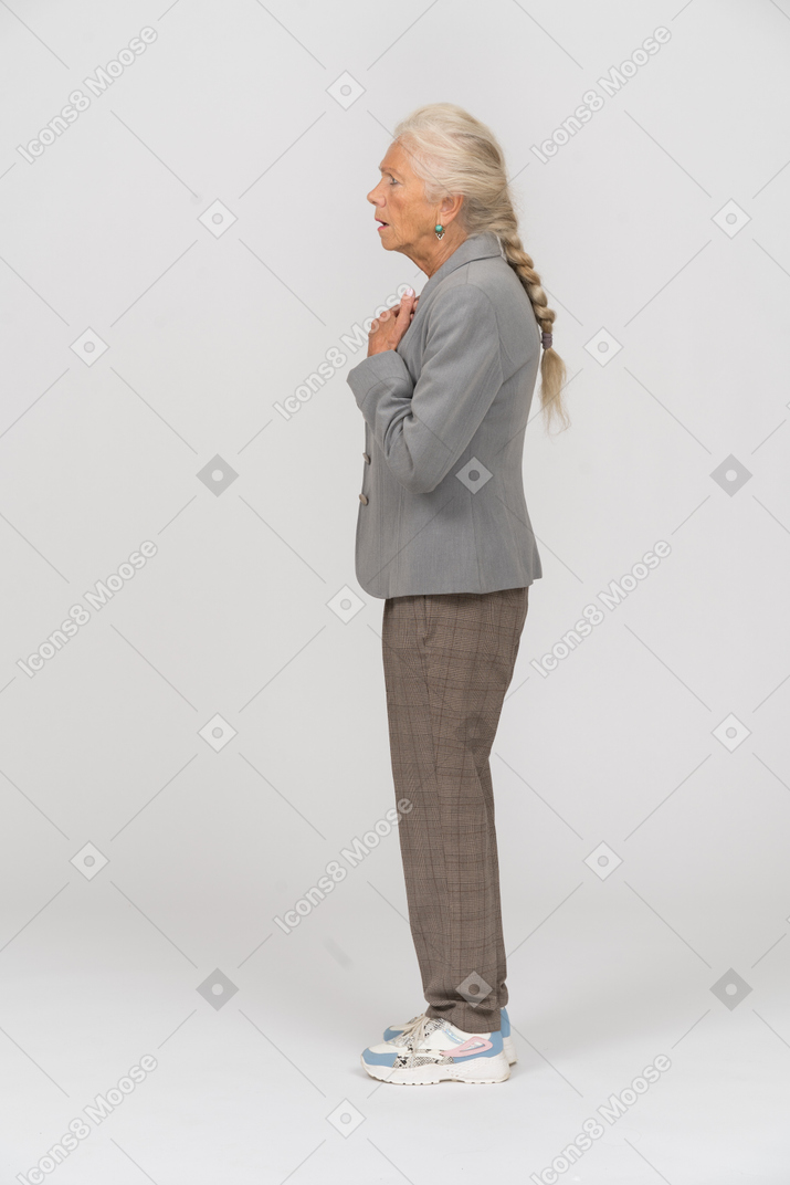 Impressionata vecchia signora in abito in piedi di profilo