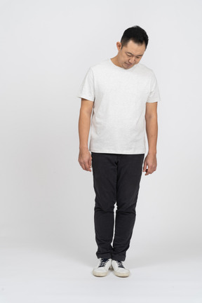 Front view of a man in casual clothes bending head down