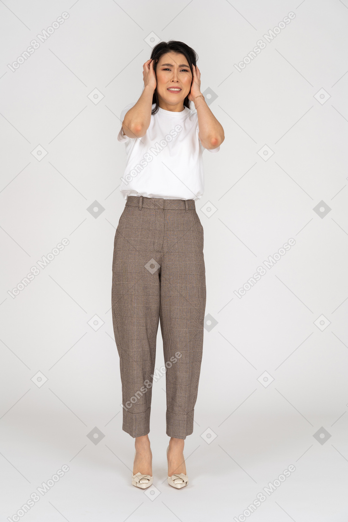 Front view of a young lady in breeches and t-shirt touching her head