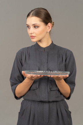 Front view of a young woman in a jumpsuit holding glass plate