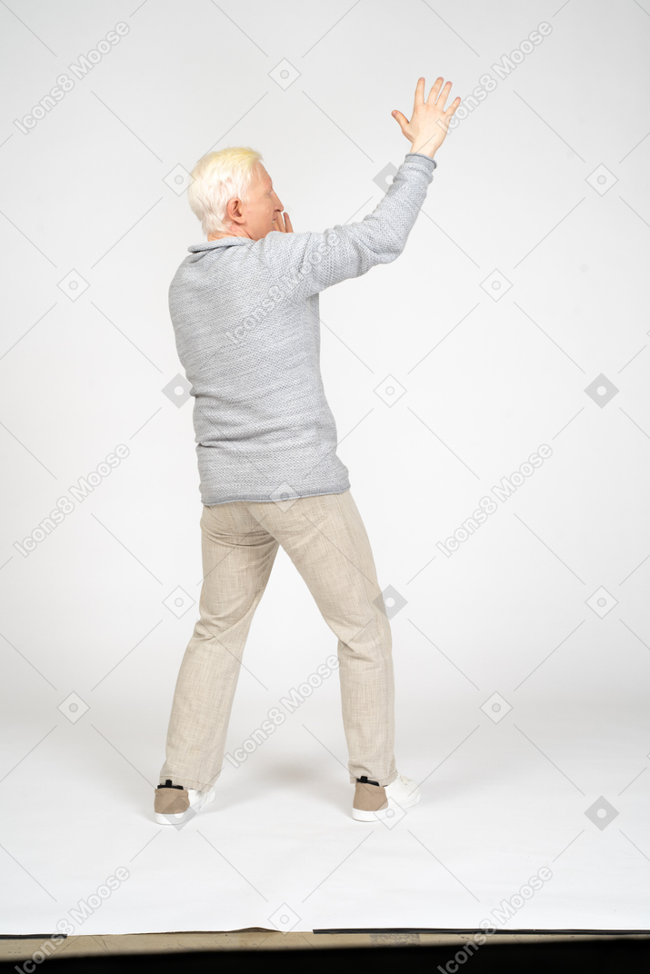 Back view of a man standing with raised arm and screaming
